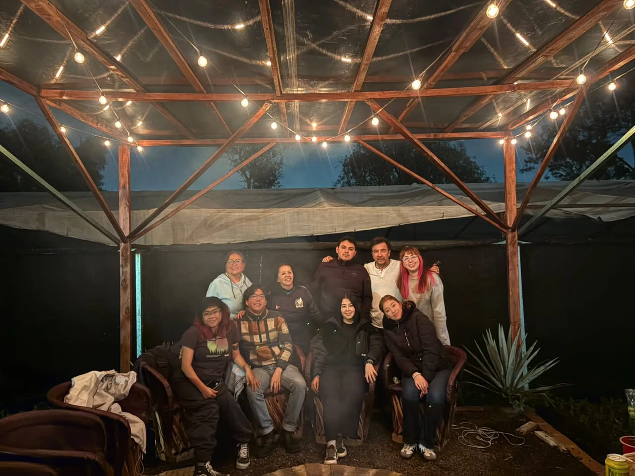 Amigos posando bajo la pérgola con luces del camping