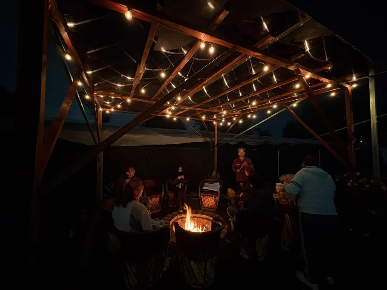 Pérgola con luces y fogata al fondo